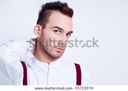 young handsome fashion model man posing in white shirt and suspenders against white background