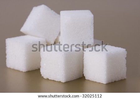 Pile of sugar on gold background. Few pieces of sugar.