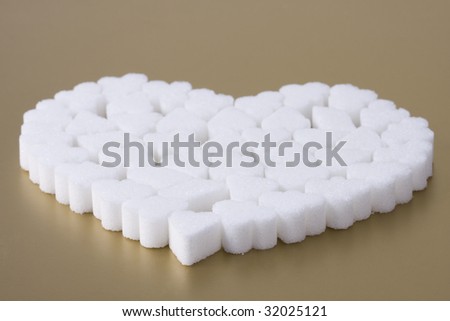 Pile of sugar on gold background. Sugar\'s heart. Few pieces of sugar.