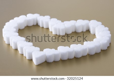 Pile of sugar on gold background. Few pieces of sugar. Sugar\'s heart