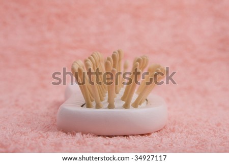 Wooden comb on peach-coloured bath towel. Hair comb close up.
