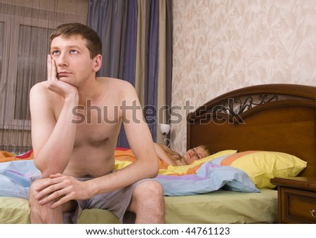Young couple in a bed bored woman. Woman and man having a disagreement. Female is sleeping and male with sad expressions.