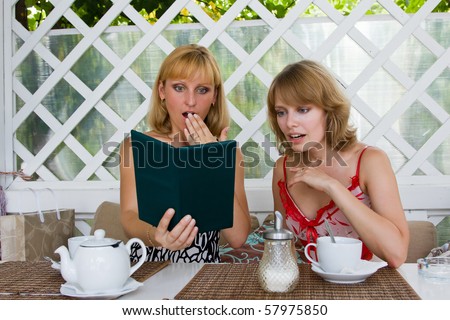 Two women expressed shock at the big bill. Friends having coffee in cafe. Female friends talking and drinking in coffee shop.