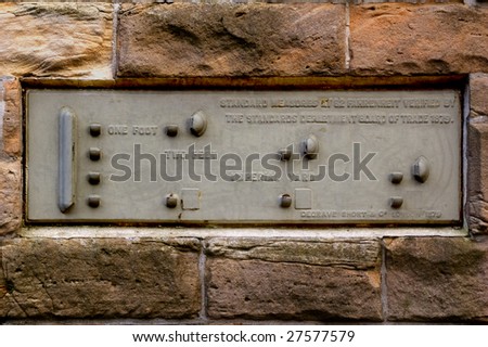 A metal plaque in a brick wall, used for market towns for standardizing imperial  measurements