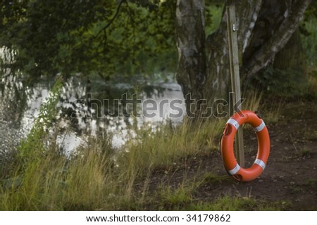 A life ring stands by the side of a lake, ready to help anybody who falls in.