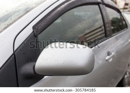 some people at defocused rain drops on the wing mirror,The concept of safety while driving.