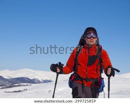 A man with glasses and a backpack goes through the snow.