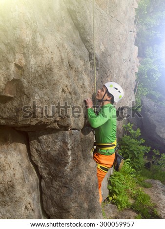 A young rock climber climbs difficult wall in a protective helmet.