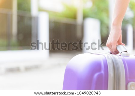 Asian girl has holding big purple bag for come back from travel and arrived at home in the evening with sunset time.