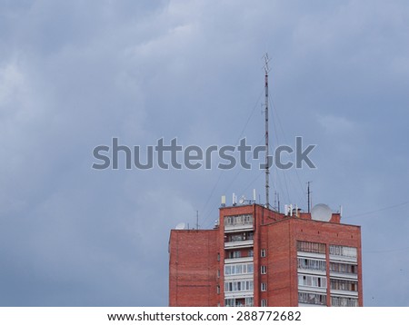 The roof of a large apartment building with antennas against thunder sky