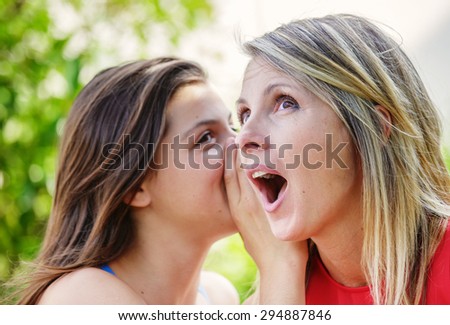 Pretty young brunette whispering in the ear of her mother
