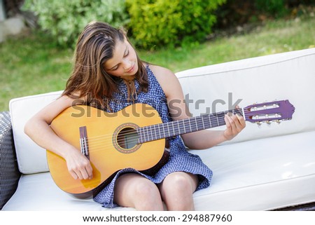 Portrait of very handsome teenager playing guitar in her garden