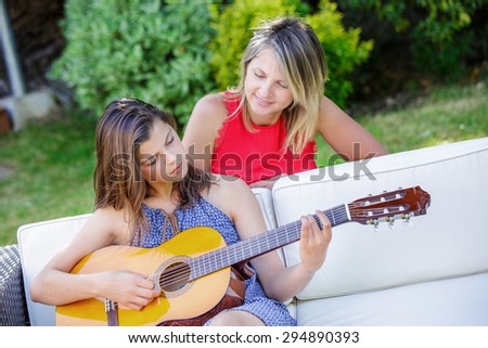 beautiful girl playing guitar in a garden with her mom