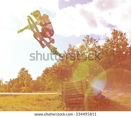 Sportsman on a mountain bike is flying in a jump from a springboard with special light lens effect