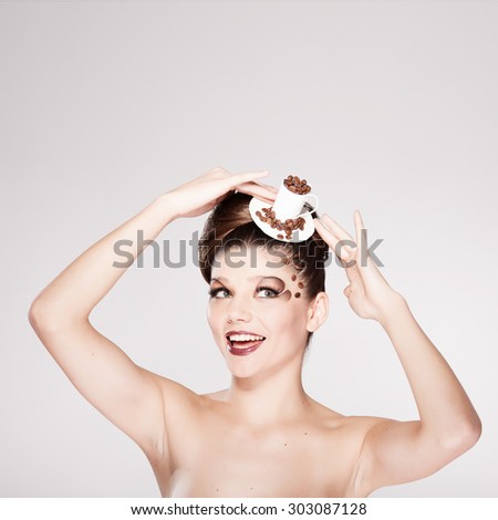Beautiful girl in a hat stylized cup of coffee with coffee beans on the face looking up