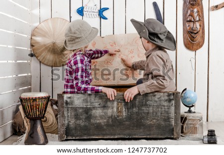 two little children in sitting in old chest study map on the wall