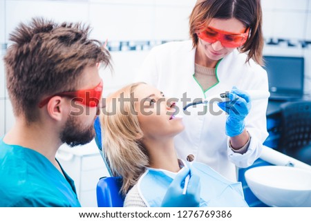 Dentists in red glasses lighting dental seal with ultraviolet lamp