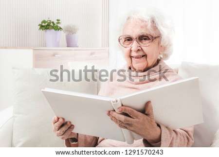 Smiling grandmother reading big white book