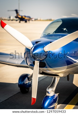 Closeup view of white propeller with red endings of the shiny blue sport plane nose