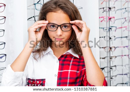 Teenage girl holding glasses standing in the optical store
