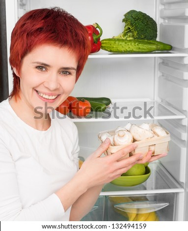 young woman with mushroom against the refrigerator with food