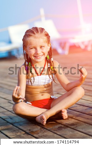 smiling cute girl on a timber floor in a yoga pose