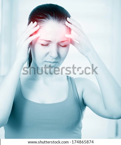 A young woman with headache holding head, monochrome photo with red as a symbol for the hardening