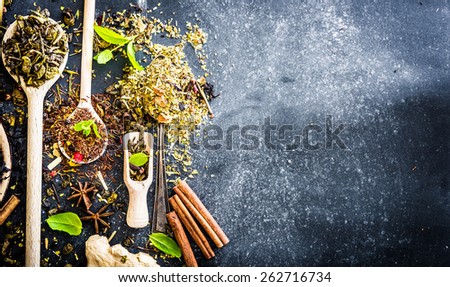 Virious kinds of tea in wooden spoons on black table