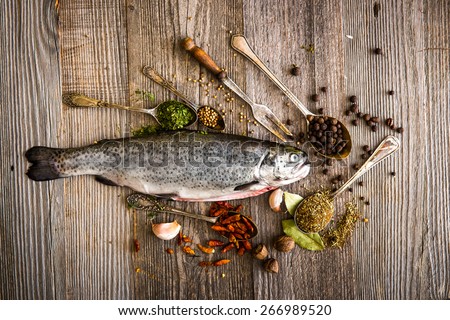 fresh trout with spices and seasonings on a dark table