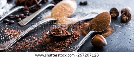 Chocolate powder cocoa and coffee spoons on the table black