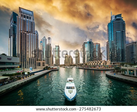 Dubai, United Arab Emirates - December 14, 2013: Modern skyscrapers and water channel with boats of Dubai Marina at sunset, United Arab Emirates