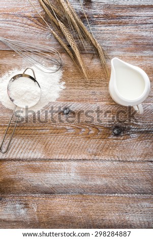 Flour sieve, wheat ears and jug on a wooden table