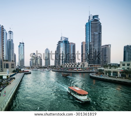 Dubai, United Arab Emirates - December 14, 2013: Modern skyscrapers and water channel with boats of Dubai Marina in evening, United Arab Emirates