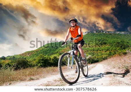 A young female riding a mountain bike outdoor at sunset
