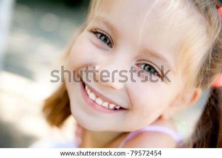 cute little girl smiling in a park close-up
