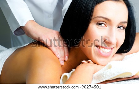 beautiful woman receiving a back massage looking at camera in a spa center