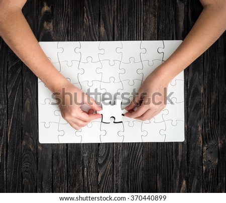 hands completing wthite puzzle with the last piece