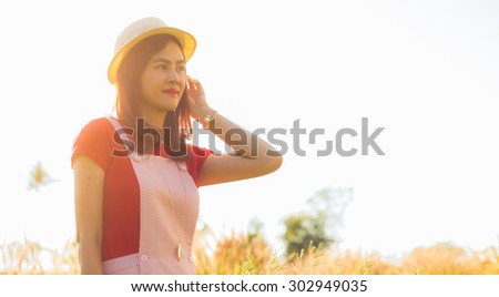 Beautiful woman with hat  she stand in the field against a golden sunset with sun flare. natural colors with lens flare
