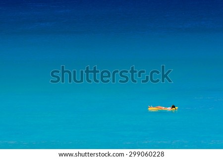Girl in white bikini relax on air bed in the blue sea. Kata Beach, Phuket, Thailand.