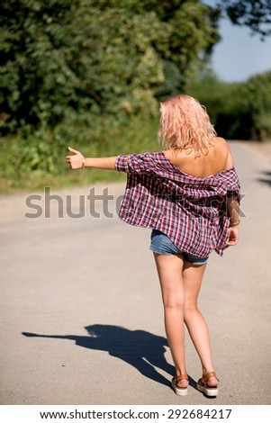 Young attractive girl in bikini with small pants hitchhiking back shot
