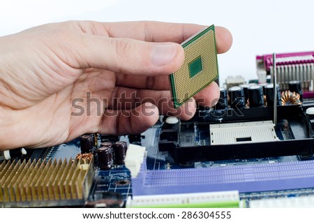The repair man holding the CPU processor in his hand in front of motherboard