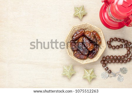 Table top view aerial image of decoration Ramadan Kareem holiday background.Flat lay date in wood basket with brown rosary & red lantern.Essential object star on rustic white wood at office desk.