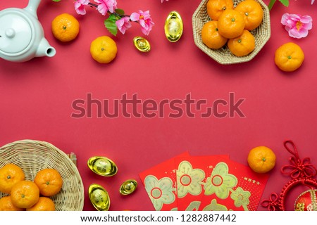 Chinese language mean rich or wealthy and happy.Table top view Lunar New Year & Chinese New Year concept background.Flat lay orange & pig doll with gold  and red pocket money card on red wallpaper.