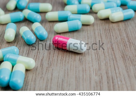 medicine background the single pink medicine capsule different all blue medicine capsules on wood table texture background.