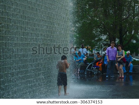 A Child Enjoys the Water Fountain at a Crowded Public Park: Crown Fountain in Millennium Park, Chicago, Illinois USA - June 14, 2015.