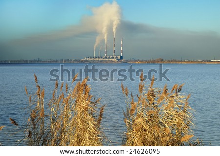 Gray smoke from the pipes of the plant on the shores of lake