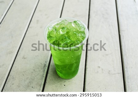 An image of green juice in plastic cup full filled by ice