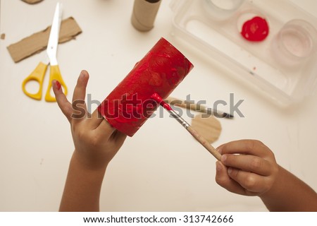 child hands with painting and cutting with scissors to make craft