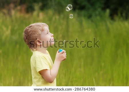boy blowing soap bubbles on a summer day