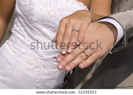 stock photo Bride and groom holding hands with wedding rings